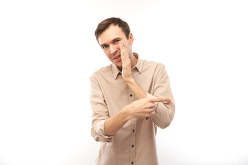 Portrait of friendly positive young man smiling pointing finger at empty copy space for text or product isolated on white background, advertising banner