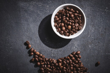White cup of freshly brewed roasted coffee beans on gray background