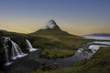 sunrise on a mountain with green meadows and waterfalls overlooking the sea in autumn and winter
