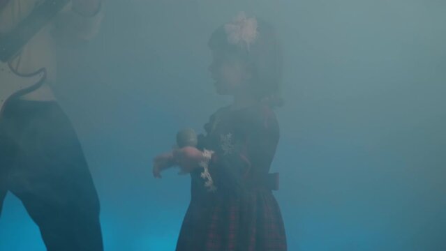 Little girl on stage in vintage dress, she sings into microphone and dances, her father plays an electric guitar. Color music is shining and smoke is billowing. Family time, creativity and hobbies