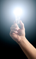 Man's hand holding lighted light bulb. 