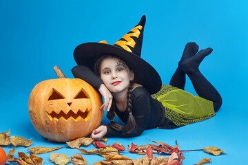 portrait of a charming little girl in a witch costume, Jack's lamps are standing around. the...
