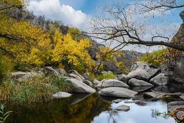 A granite canyon in the bed of the Mertvovod River in the village of Aktove, Ukraine. Colorful leaves of trees in the autumn landscape, colors of leaf-fall.
