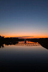 A picturesque sunset on the banks of the river overlooking the bridge.