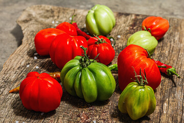 Green and red ribbed tomatoes on a vintage wooden stand. American or Florentine variety