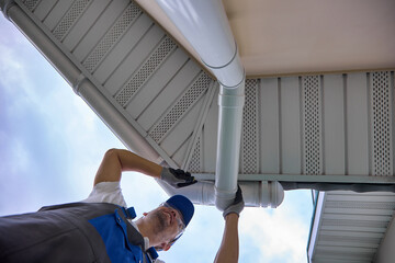 View from below installation modern rainwater drainage system from the roof on the corner of the...
