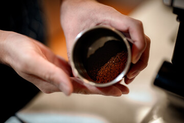 Barista making a Geisha coffee, pouring hot water from kettle over a ground coffee powder
