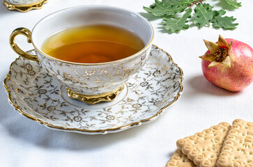 Cup of tea with biscuits on table with autumn leaves and pomegranate 