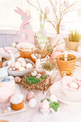 Obraz na płótnie Canvas happy easter and spring holidays time. festive tablescape set decor. traditional dinner food easter eggs and baked cakes on table at home. rabbit and willow. pale pop pastel blue and pink color. flare