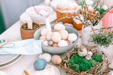 happy easter and spring holidays time. festive tablescape set decor. traditional dinner food easter eggs and baked cakes on table at home. rabbit and willow. pale pop pastel blue and pink color