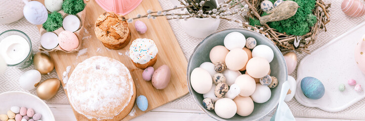 happy easter and spring holidays time. festive tablescape set decor. traditional dinner food easter eggs and baked cakes on table at home. pale pop pastel blue and pink color. top view. banner