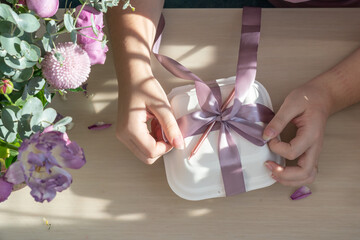 Cake packaging. The girl ties the ribbon to the packing box.