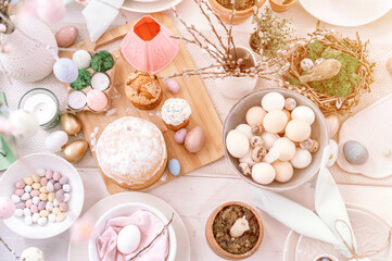 happy easter and spring holidays time. festive tablescape set decor. traditional dinner food easter eggs and baked cakes on table at home. pale pop pastel blue and pink color. top view. flare