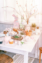 happy easter and spring holidays time. festive tablescape set decor. traditional dinner food easter eggs and baked cakes on table at home. rabbit and willow. pale pop pastel blue and pink color. flare