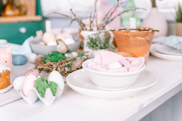 happy easter and spring holidays time. festive tablescape set decor. traditional dinner food easter eggs and baked cakes on table at home. rabbit and willow. pale pop pastel blue and pink color
