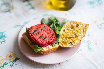 red homemade vegan beetroot hamburger seen on table with salad and bread. Beet are used as a substitute to meat.