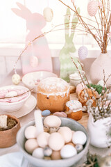 happy easter and spring holidays time. festive tablescape set decor. traditional dinner food easter eggs and baked cakes on table at home. rabbit and willow. pale pop pastel blue and pink color. flare