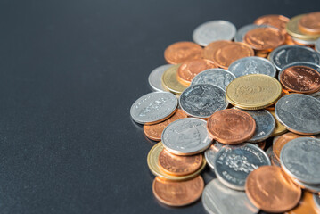 Heap coins on black table with space.