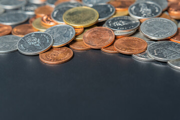 Heap coins on black table with space.
