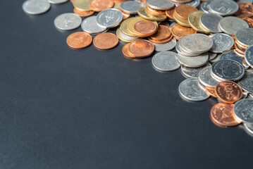 Heap coins on black table with space.