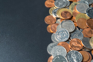 Heap coins on black table with space.