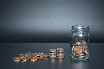 Thailand coins in jar with heap coins on black background with space