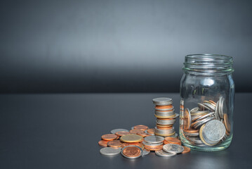 Thailand coins in jar with heap coins on black background with space
