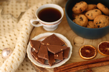 Various Christmas decorations, cup of tea or coffee, sweets, small presents, knitted blanket and candles. Selective focus.