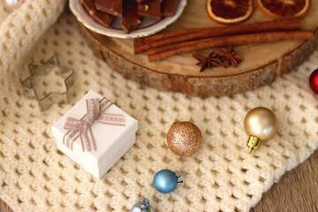 Various Christmas decorations, cup of tea or coffee, sweets, small presents, knitted blanket and candles. Selective focus.