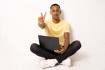 Smart young african american student using laptop showing peace symbol isolated over white background