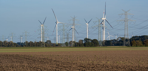 Stromnetz und Strommast Leitungen und im Hintergrund Windkraftanlagen zur Energiegewinnung - 541717085