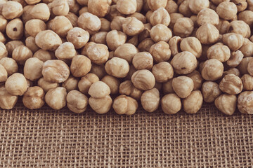 Roasted hazelnuts on a background of burlap. Heap of nut kernels. Copy space for text. Close-up.