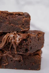Tuinposter Slices of chocolate brownies on each other, close-up © Nina Ljusic/Wirestock Creators