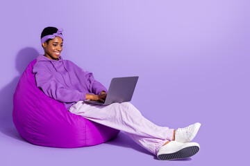 Photo of freelancer programmer transgender sit bean bag typing pc wear headband hoodie isolated purple color background