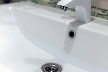 running clean water flows from a tap into a white sink. plumbing