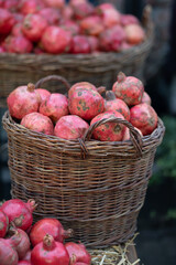 Harvest of ripe pomegranate on dry straw and wicker baskets at outdoor farmers market in Tbilisi Georgia. Vegetarian healthy food