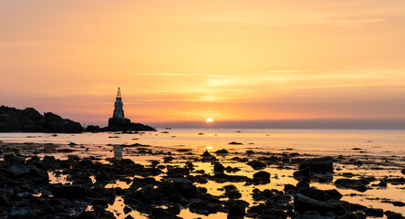 sunrise on the Bulgarian Black Sea coast in Athopol with the harbor lighthouse and rocky shore