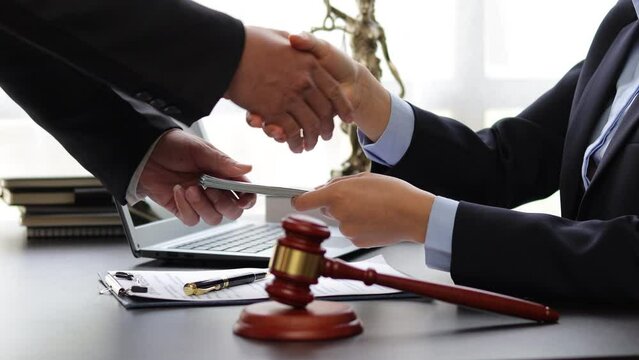 Business people shaking hands and bribe to an attorney to help a lawyer win a court case. The concept of bribing lawyers and paying lawsuits.