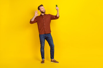 Full size photo of positive nice person hold telephone make selfie arm palm waving hi isolated on yellow color background © deagreez