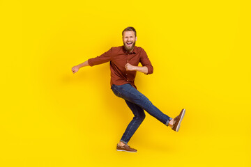 Fototapeta na wymiar Full length portrait of energetic satisfied young man dancing chilling isolated on yellow color background