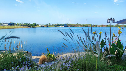 The flower garden with the blue sky and beautiful lake in the park.