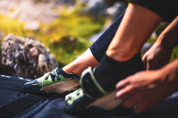 Sporty woman puts on boulder shoe in the afternoon. Falzarego pass, Dolomites, South Tirol, Italy,...