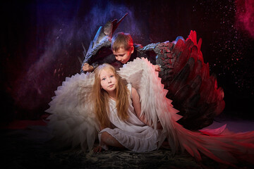 Boy in black clothes and girl in white dress with angel or demon wings. Concept of struggle of good...