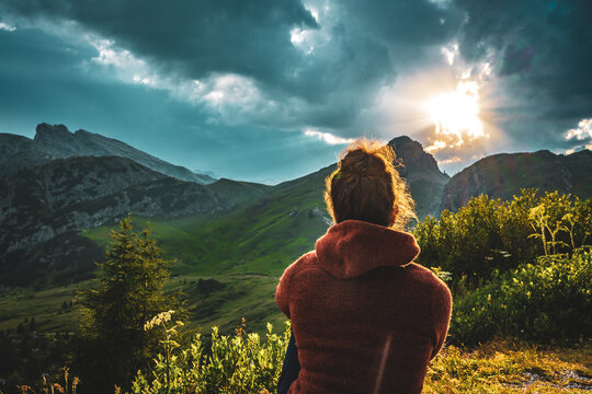 Sporty woman in outdoor jacket watches beautiful mountain scenery at sunset. Falzarego pass, Dolomites, South Tirol, Italy, Europe.