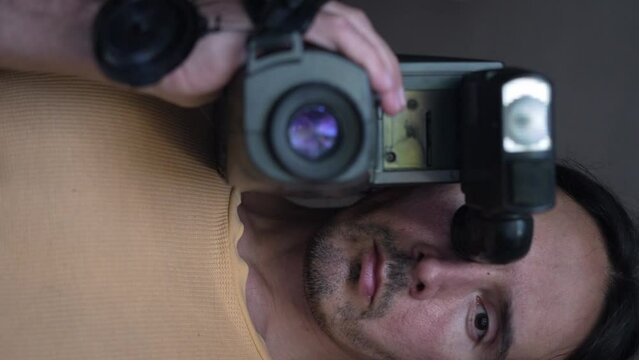 A handsome cameraman with a retro camcorder slow motion, vertical view