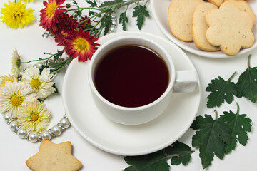 A cup of tea on a table with flowers on a white background. Tea and biscuits for breakfast