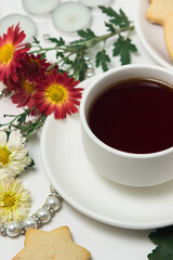A cup of tea on a table with flowers on a white background. Tea and biscuits for breakfast