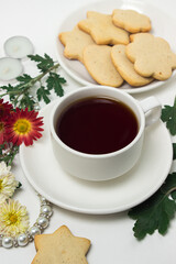 A cup of tea on a table with flowers on a white background. Tea and biscuits for breakfast