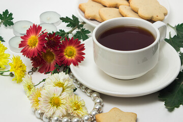 A cup of tea on a table with flowers on a white background. Tea and biscuits for breakfast