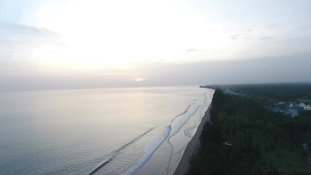 Aerial view of a beach in Padang with tropical trees overlooking the calm sea on a sunny morning